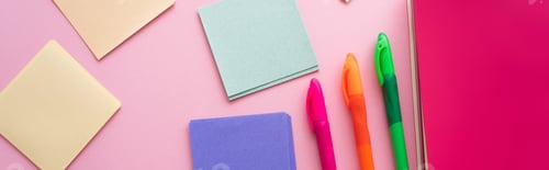 Preview: top view of colorful pens near bright notebook and blank paper notes on pink, banner