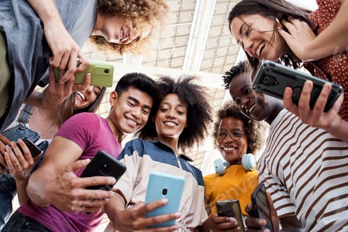 Preview: Low angle view of a group of young teenagers holding cell phones. Concept of technology, connection.