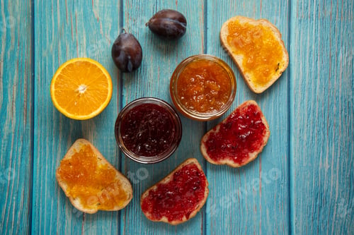 Preview: Orange and plum confiture in a glass jar and on the toast breads