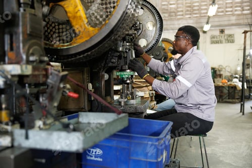 Preview: african black male worker working in heavy metal industry factory punching stamping steel machine