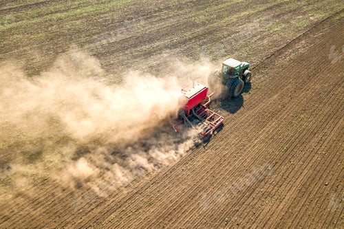 Preview: Tractor cultivating ground and seeding a dry field.