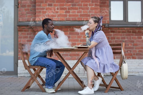Preview: Side view of two young intercultural colleagues smoking at meeting