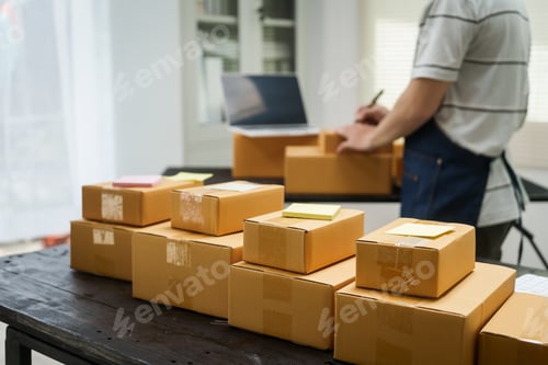 Preview: A man is working at his desk, preparing parcel boxes for shipment.He checks packs items carefully