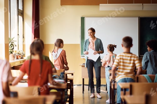 Preview: Happy teacher and her elementary students in the classroom at school.