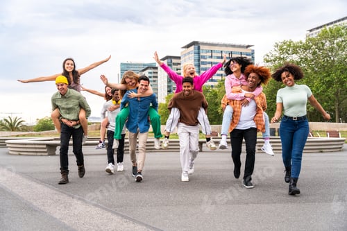 Preview: Happy playful multiethnic group of young friends bonding outdoors