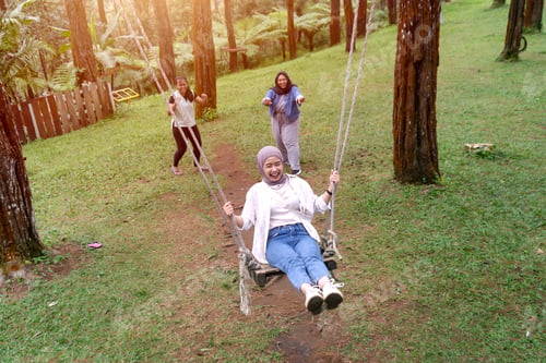 Preview: Happy Young Asian Indonesian Women Playing on a Swing in Pine Forest Park
