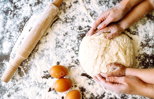 Preview: Close up hands of mother and son kneading a dough on a wooden table. Family cooking at home together