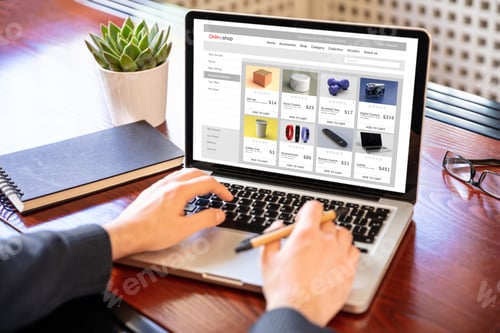 Preview: Online shop website developer working with a laptop, office desk background.