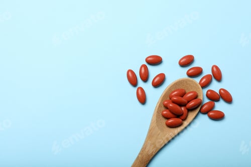 Preview: Wooden spoon with pills on light blue background, flat lay. Space for text