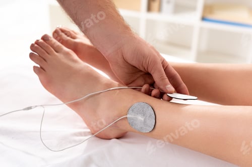Preview: Cropped view of doctor holding electrode near patient leg during electrode treatment in clinic