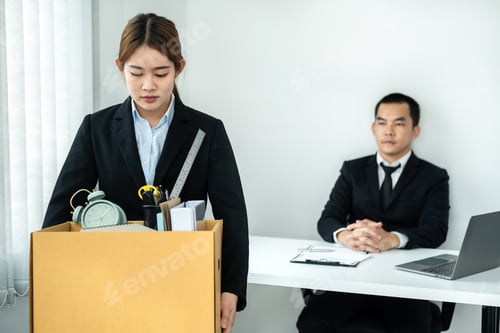 Preview: Woman employee is stressed and carrying personal belongings in brown cardboard box to walking out