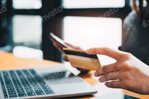 Preview: Young woman holding credit card and using laptop computer. Online shopping concept