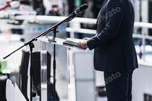 Preview: Male Speaker Standing In Front Of Microphones