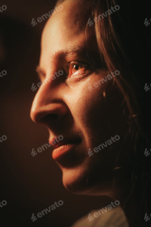 Preview: Closeup portrait of a young blonde woman smiling in the dark