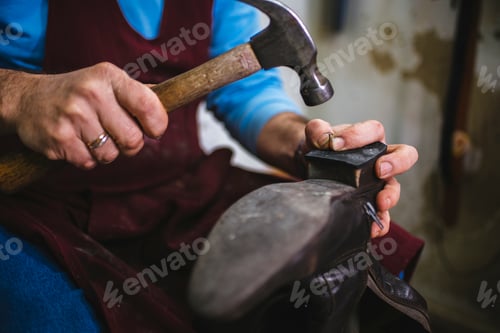 Preview: Shoemaker repairing sole of boot with hammer and nails