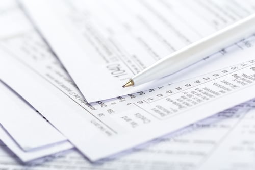 Preview: Stacks of papers with writing instruments on a table in an office setting during the day