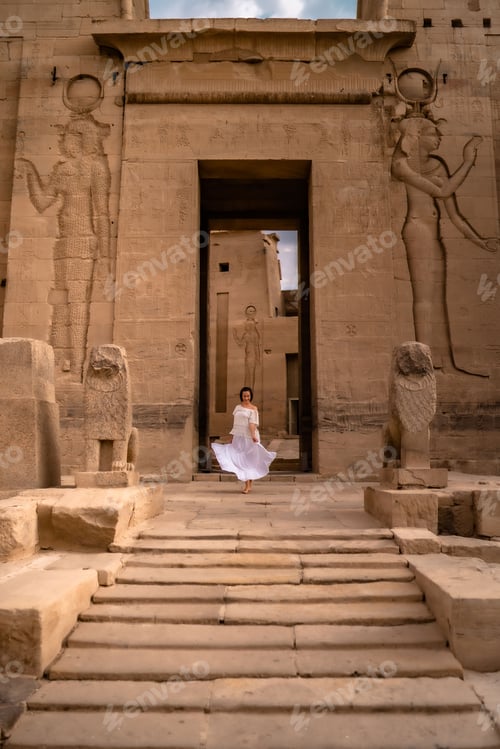 Preview: Vertical shot of a woman in a white dress standing at the entrance of the Philae temple complex.