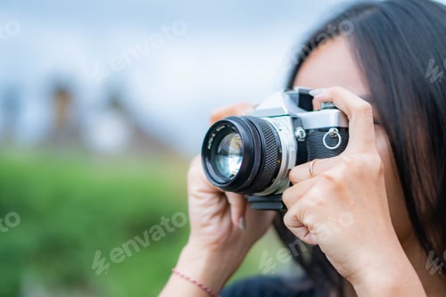 Preview: Person taking a photo with a vintage camera outdoors