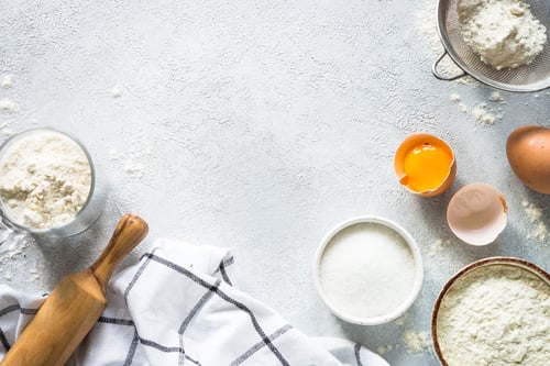 Preview: Baking background ingredients. Flour, sugar, eggs and rolling pin at light stone table.