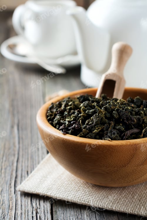 Preview: Oolong green tea in white bamboo bowl on a wooden table. Selective focus