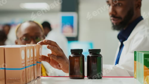 Preview: Male assistant showing bottle of pills to customer