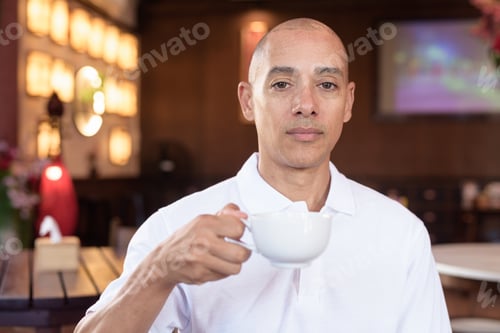 Preview: Bald Hispanic man in white polo shirt sitting in Chinese style coffee shop drinking coffee