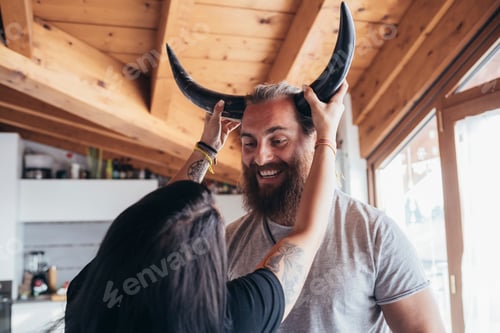 Preview: Playful moment as a person puts horns on a smiling man's head.