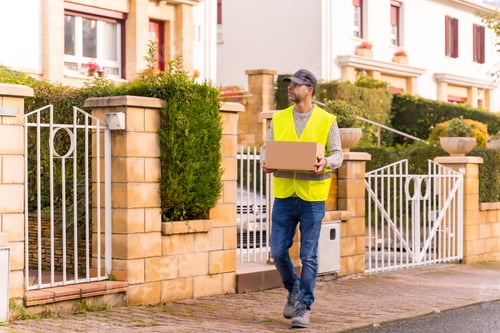 Preview: Package delivery driver from an online store, with a box in hand looking for the house