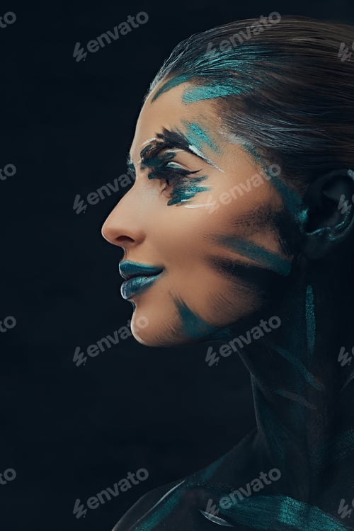 Preview: A young sensual girl with creative makeup. Blue and black shadows painted on her face.
