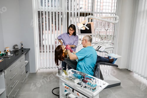 Preview: Two dentists, man and woman perform surgical operation on a patients tooth.