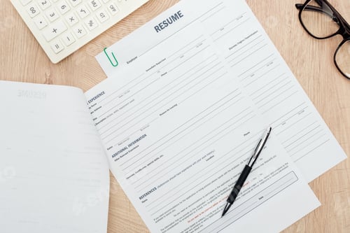 Preview: top view of glasses, pen, calculator and resume templates on wooden surface