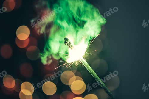 Preview: Close-up of green holiday sparkler in the dark