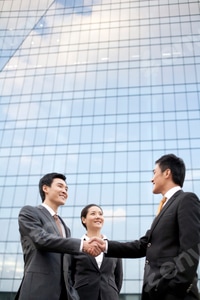 Preview: Businessmen shaking hands in front of a tall building