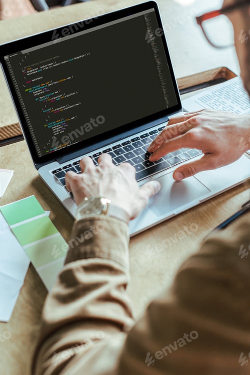Preview: Cropped view of developer working with laptop at table in coworking space