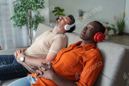 Preview: Serene couple relaxing on sofa, enjoying music with headphones