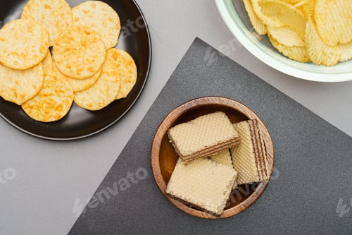 Preview: Flat lay of snack, Crispy potato chip and wafer in various containers on gray background