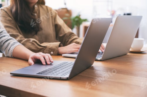Preview: People using and looking at laptop computer on wooden table together
