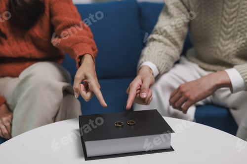 Preview: Couple pointing at wedding rings on a book symbolizing divorce