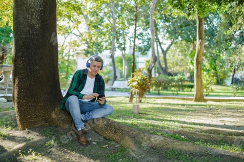 Preview: Gray-haired man listening to music with headphones and typing on his cell phone