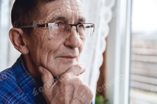 Preview: Senior standing at the window and thinking about something or fo
