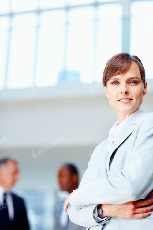 Preview: Female executive standing casually with colleagues in background