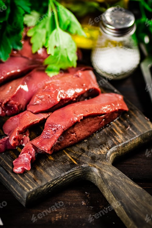 Preview: Pieces of raw liver on a cutting board with parsley and spices.