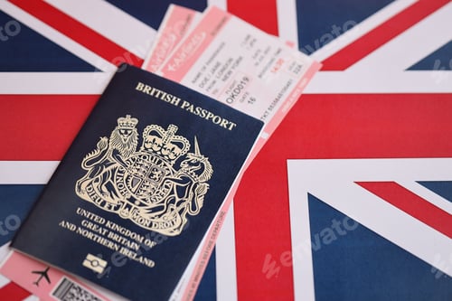 Preview: Blue British passport with airline tickets on national flag background close up