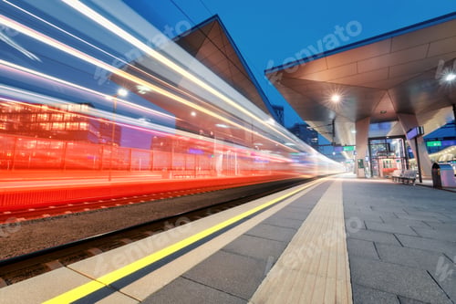 Preview: High speed train in motion on the railway station at night. Blurred red modern passenger train