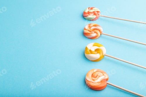 Preview: Four lollipop candies on blue background. copy space, side view