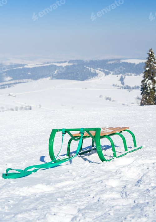 Green Sled on Snowy Winter Hillside