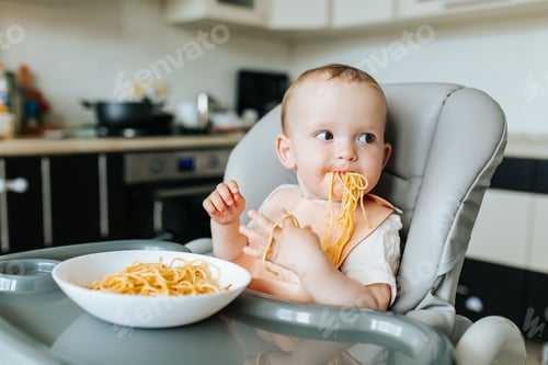 Visualização: Criança engraçada com macarrão caseiro e molho de tomate.