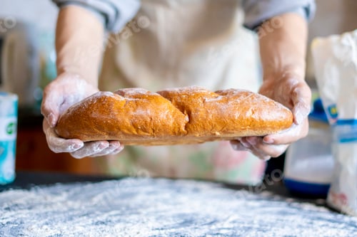 Preview: baker hands holding freshly cooked long loaf bread f