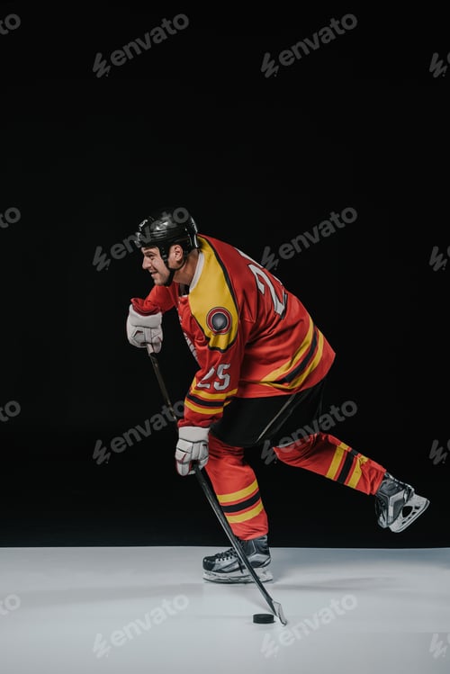 Preview: side view of ice hockey player playing hockey and looking away on black