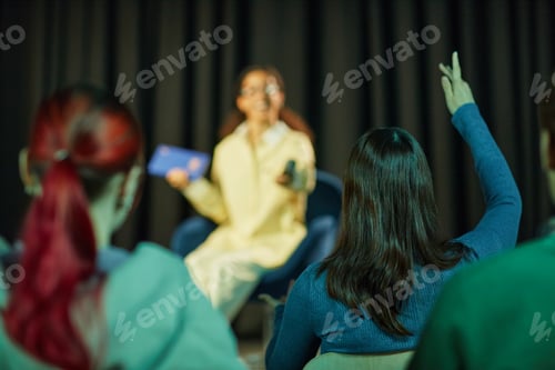 Preview: Teenage Girl Raising Hand While Listening to Young Adult Woman Giving Presentation